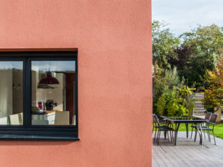Extension d'une maison au couleur terracotta avec sa terrasse de couleur grise pour un rendu moderne